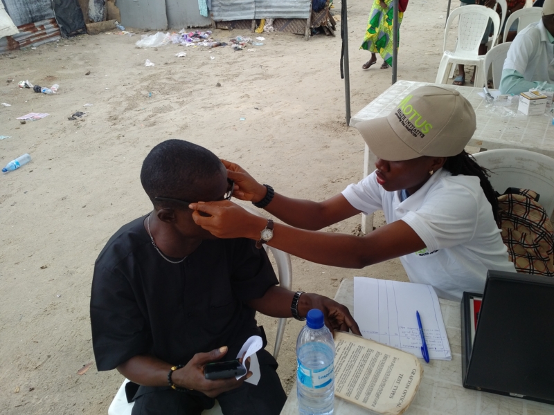 Dr Cynthia Ike (Optometrist) of Motus Health Initiative trying out a pair of free eyeglasses on a beneficiary at the Aboki estate Lekki Free Medical outreach.